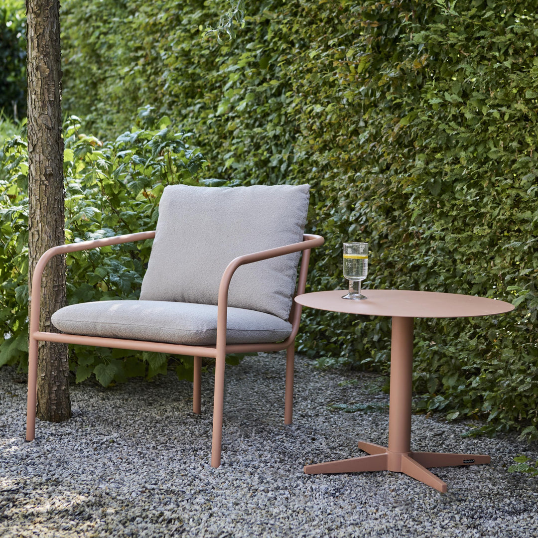 Brafab Bendt hagestol i fersken med beige puter og sidebord i hagen