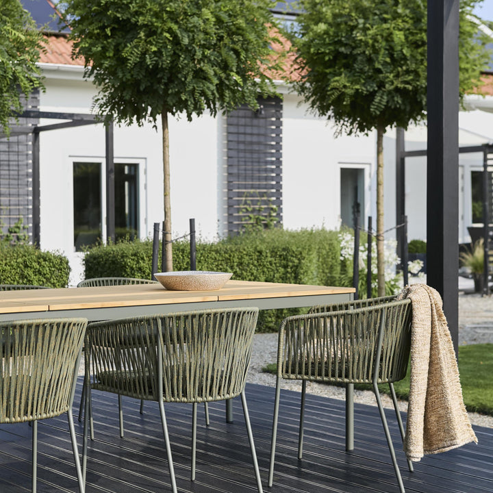 Brafab Piatto spisestoler i grønn rundt teakbord på mørk terrasse med hagehus