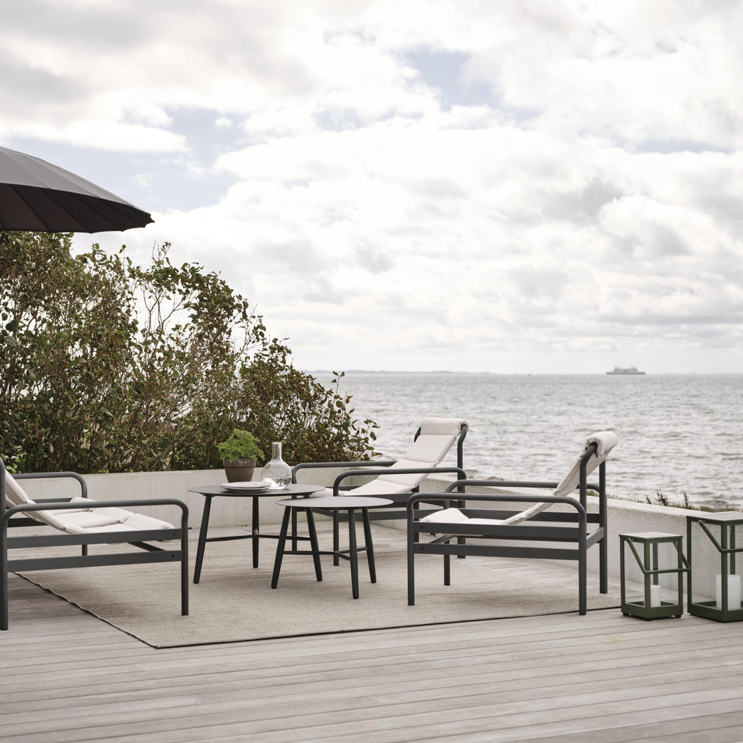 Brafab Vannes hagebord i antrasitt i loungegruppe på tredekke mot havet, med parasoll og lyse puter.