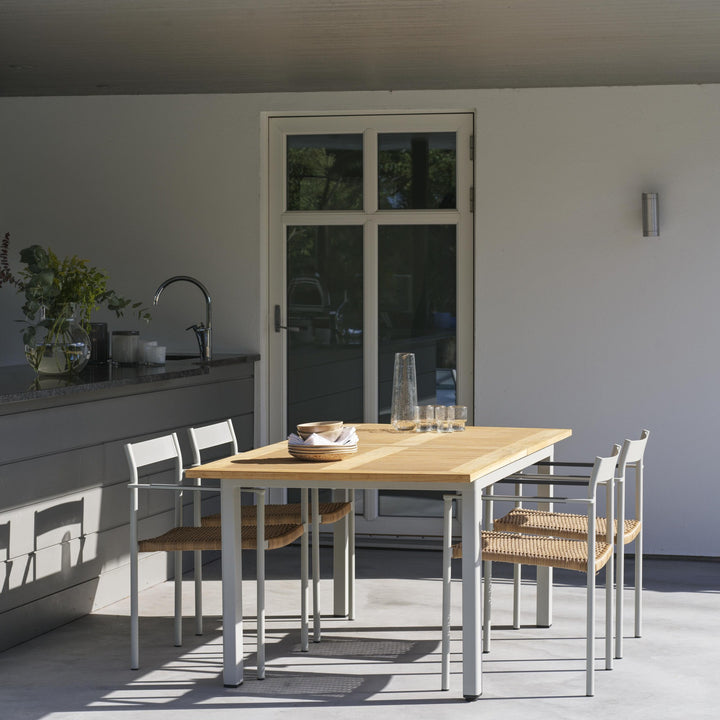 Brafab Lyon spisebord i teak med lyse ben, dekket på terrasse med stoler, eukalyptus og glass