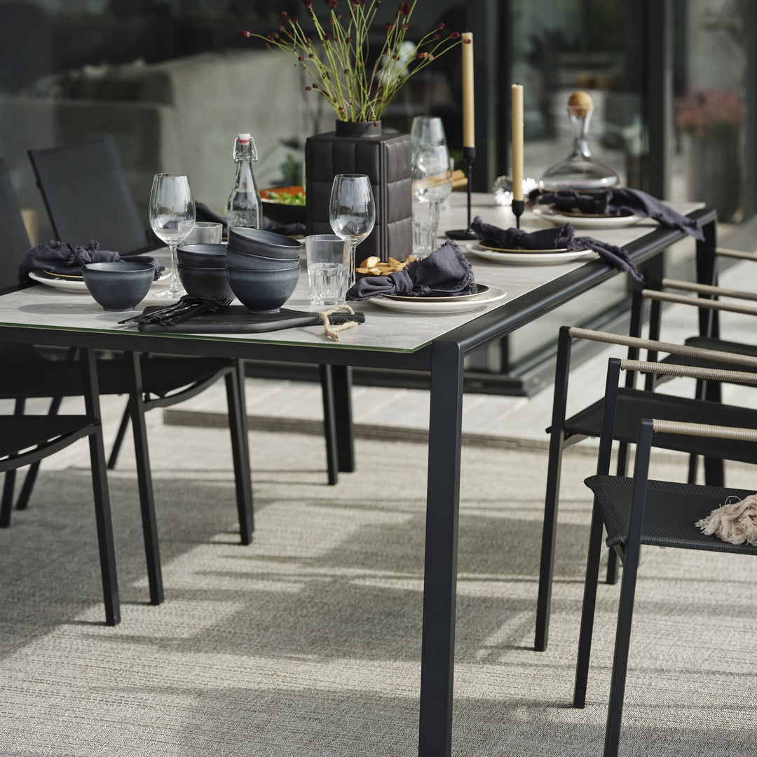 Brafab Lyra spisebord med grå keramisk plate, dekket til middag med sort servise på terrasse