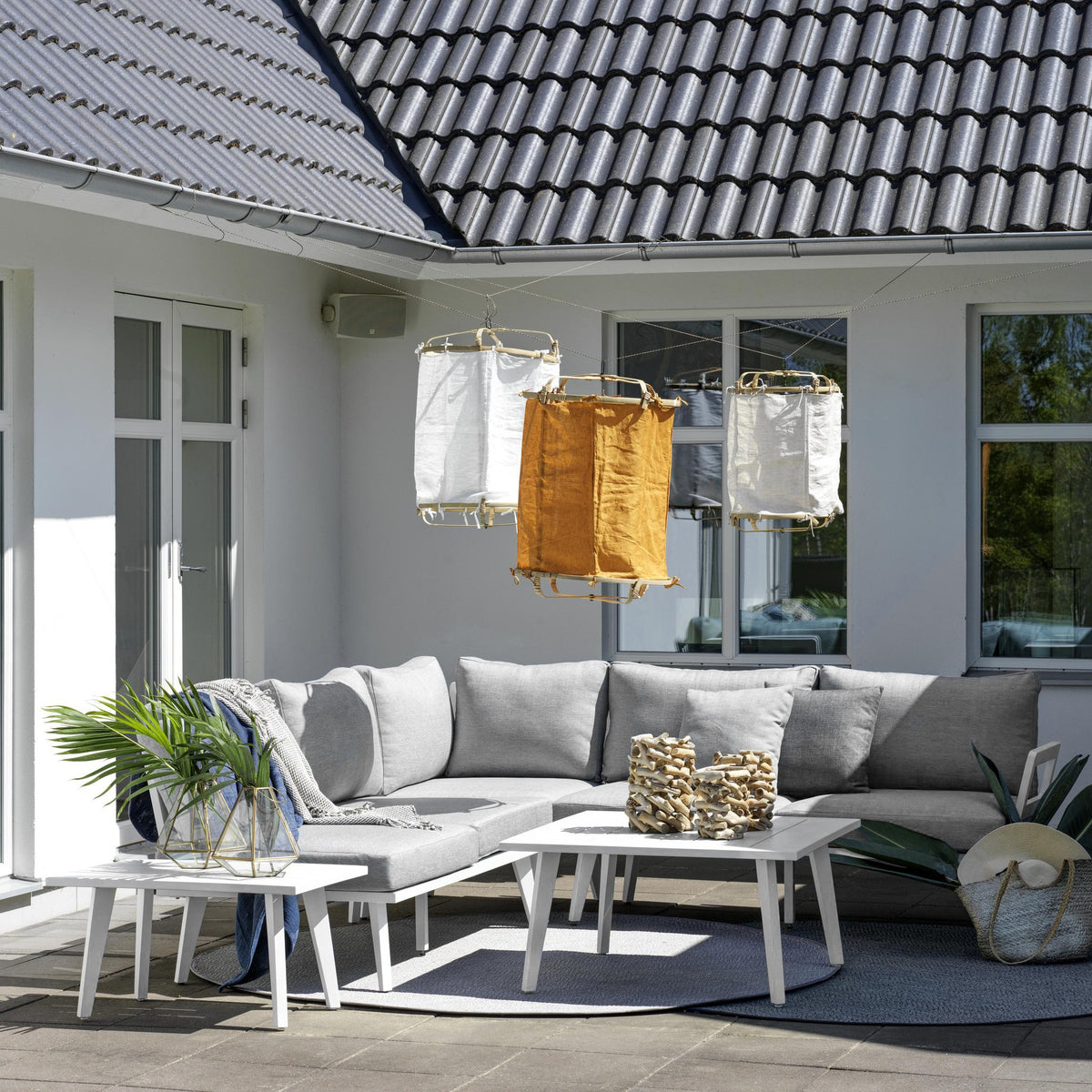 Brafab Villac sofabord i hvit foran grå hjørnesofa på terrasse, med puter og lyslykter