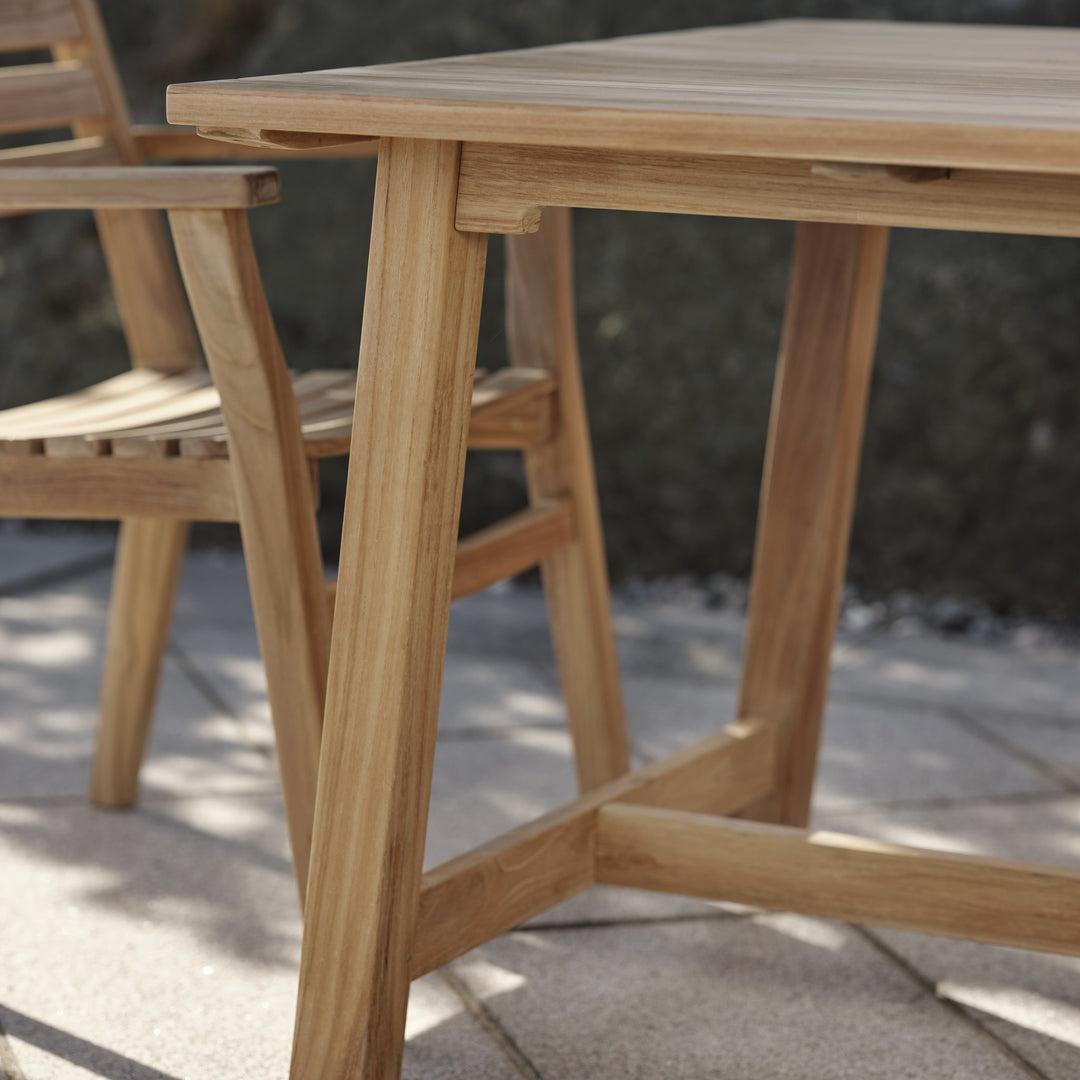 Brafab Keros spisebord i teak, nærbilde av bordkant og bein på solfylt terrasse