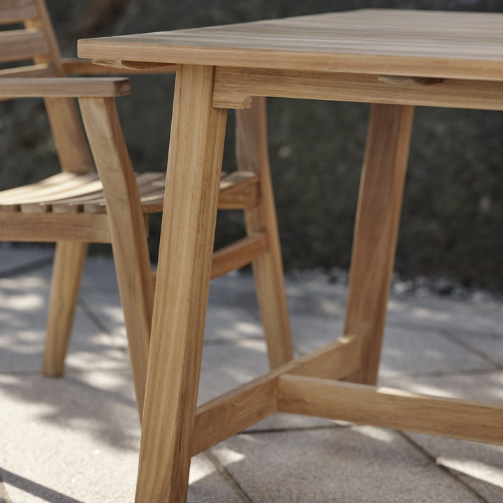 Brafab Keros spisebord i teak, nærbilde av bordkant og bein på solfylt terrasse