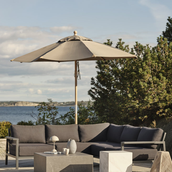 Brafab Zten sofabord i grå marmorlook på terrasse med loungesofa, parasoll og utsikt mot sjøen