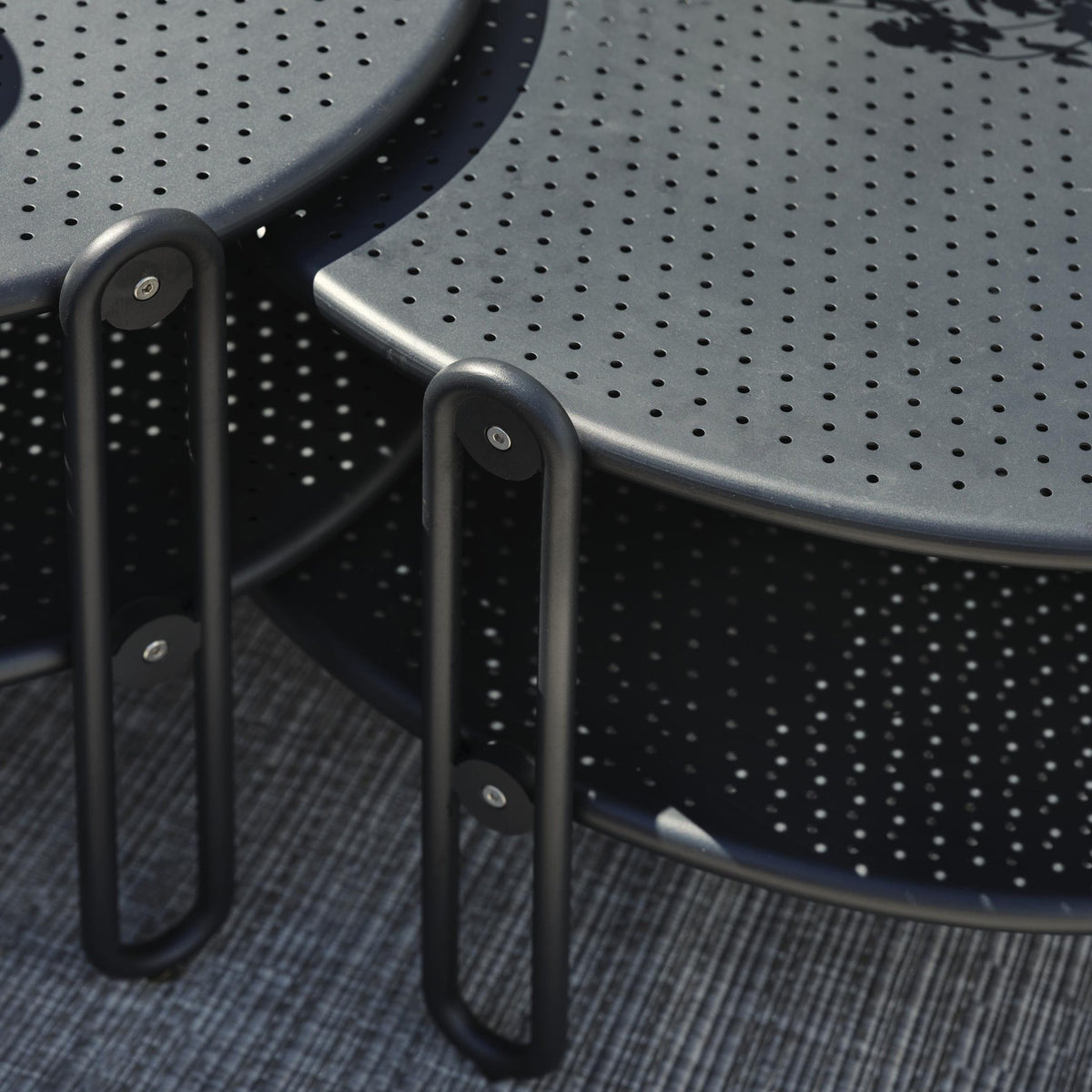 Brafab Blixt sofabord i sort, runde perforerte bord med bøyleben, nærbilde på terrasse
