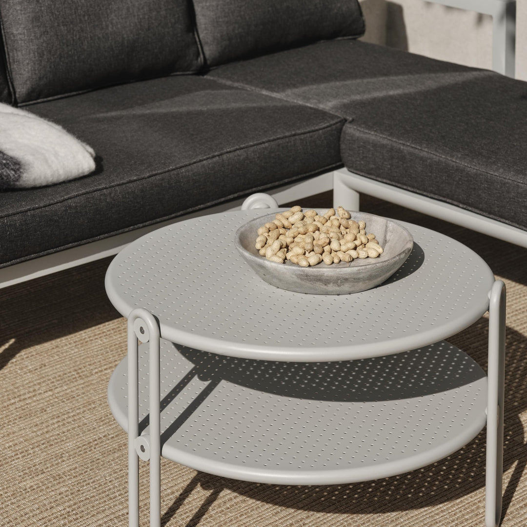 Brafab Blixt sofabord, lyst grått metallbord i to plan med skål, ved mørk grå sofa på juteteppe