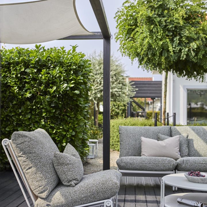 Brafab Blixt sofabord i lys grå på terrasse med grå bouclé-sofa, lenestol og grønn hekk