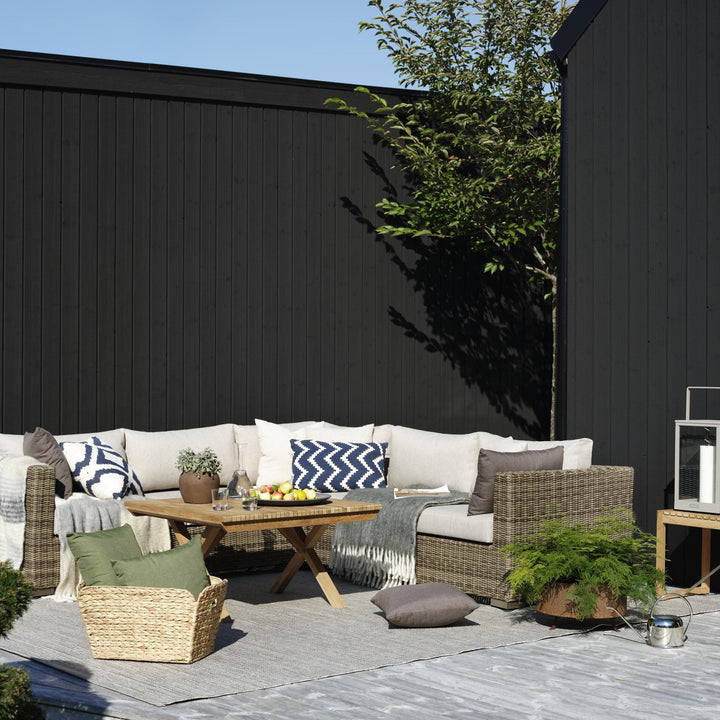 Brafab Julita sofabord i natur teak foran beige hjørnesofa i rotting på terrasse