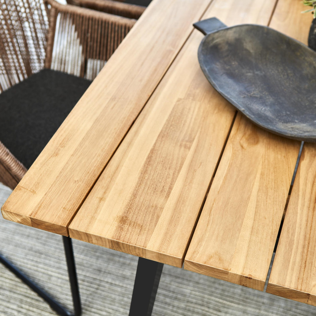 Brafab Laurion spisebord i teak med sort fat, nærbilde av planker og brun taustol