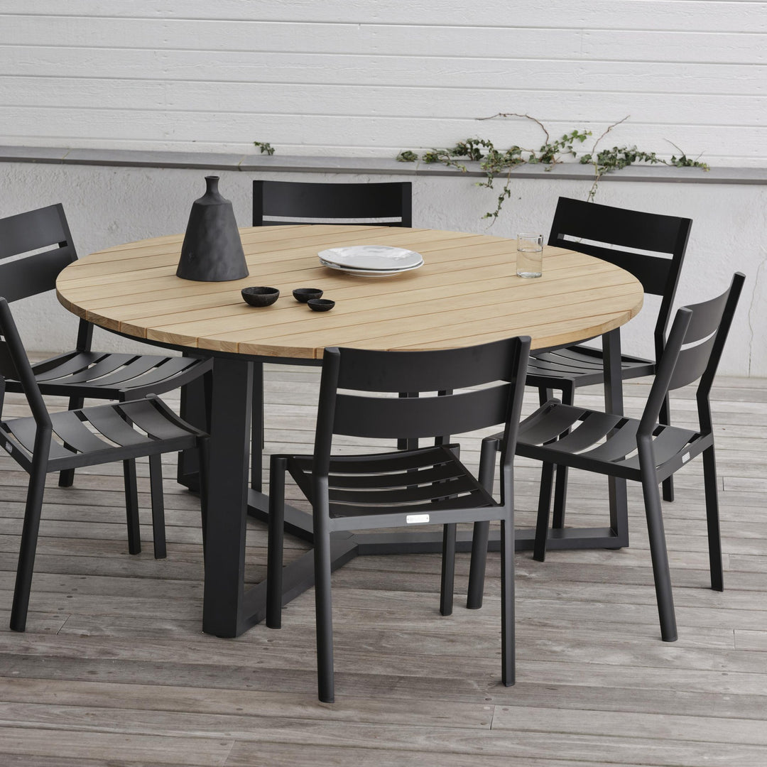 Brafab Laurion rundt spisebord i natur/sort med sorte stoler på terrasse ved hvit vegg