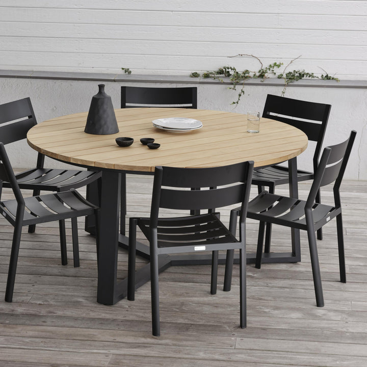 Brafab Laurion rundt spisebord i natur/sort med sorte stoler på terrasse ved hvit vegg