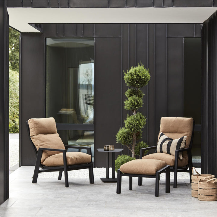 Brafab Slide sidebord i sort mellom to lenestoler med beige puter ved mørk fasade