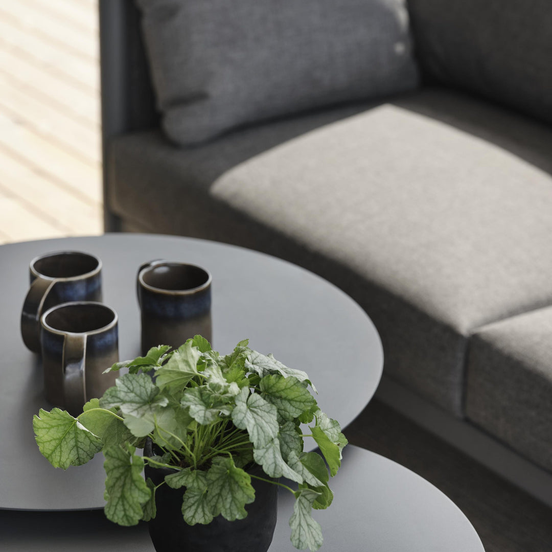 Brafab Mill sofabord i antrasitt med grønn plante og keramikkrus ved grå utesofa