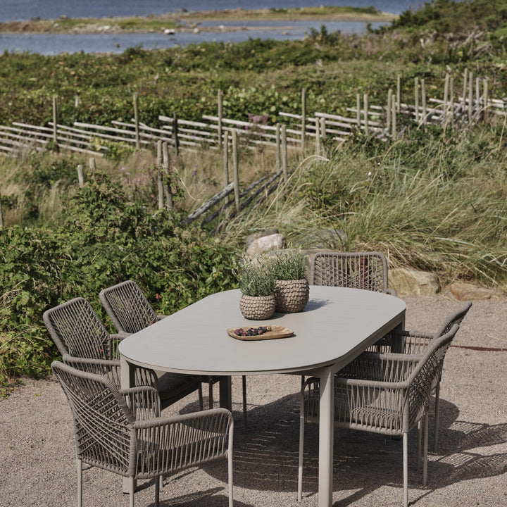 Brafab Lomma Elipse spisebord i grått med flettede stoler på terrasse ved kysten