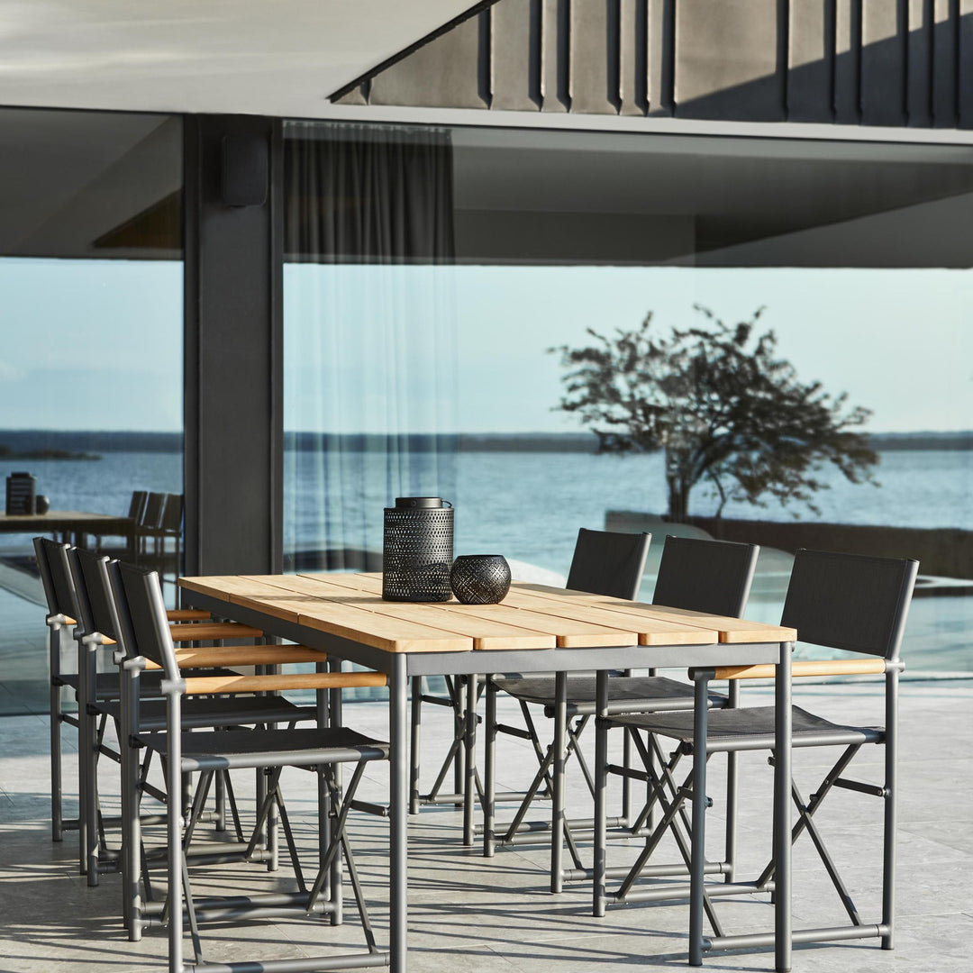 Brafab Nox Bamboo spisebord i teak med sorte klappstoler og havutsikt