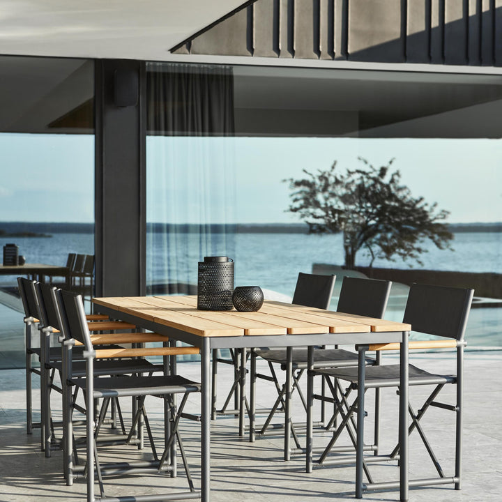 Brafab Nox Bamboo spisebord i teak med sorte klappstoler og havutsikt