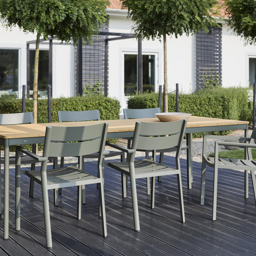 Brafab Nox Bamboo spisebord i teak med grågrønne stoler på terrasse, hvitt hus