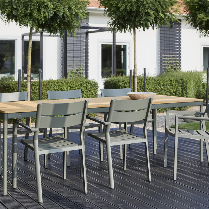 Brafab Nox Bamboo spisebord i teak med grågrønne stoler på terrasse, hvitt hus