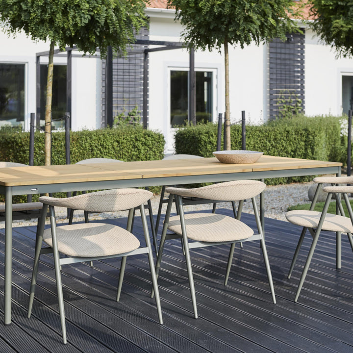 Brafab Nox Bamboo spisebord i teak med beige flettede stoler på terrasse, hvitt hus