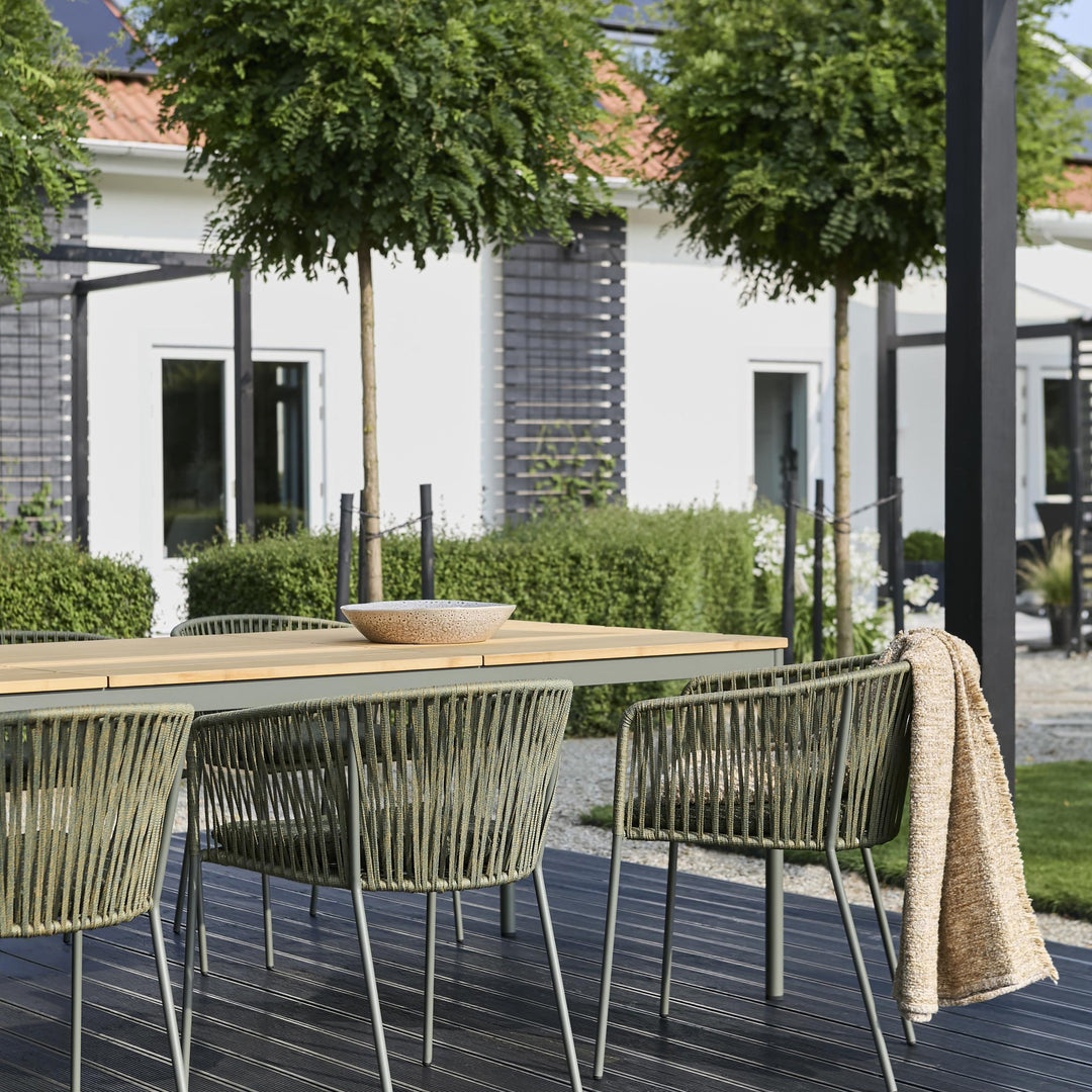 Nox Bamboo spisebord i bambus med grønne rebstoler på terrasse foran hvitt hus
