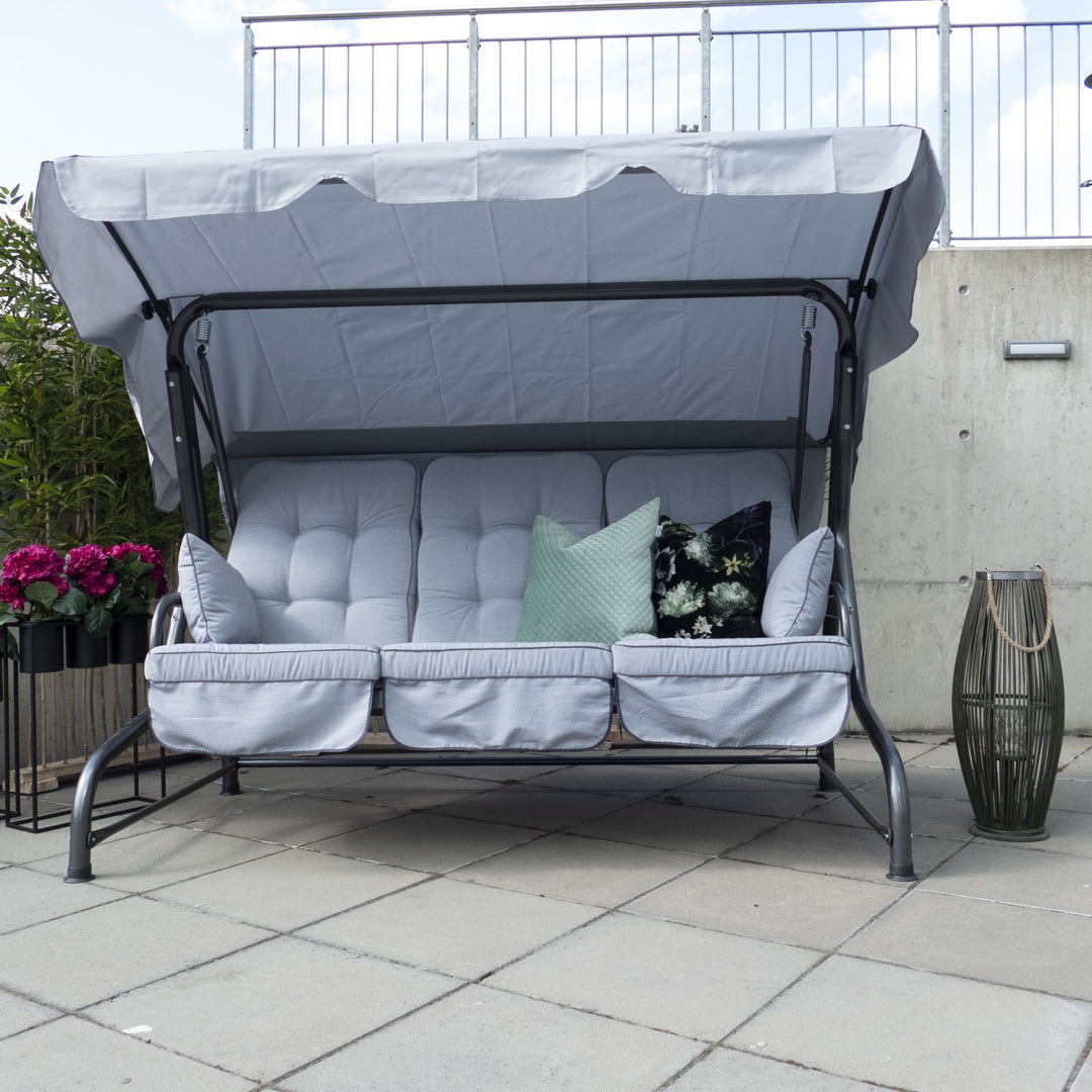 Brafab Wien hammock i sort med tak og myggnett på gressplen, person ligger og leser, hus i bakgrunnen