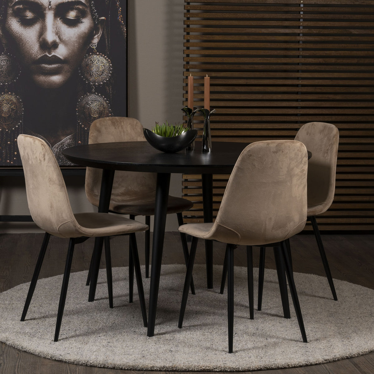 Trend spisestol i beige velur med sorte ben ved rundt sort spisebord, kunst på vegg