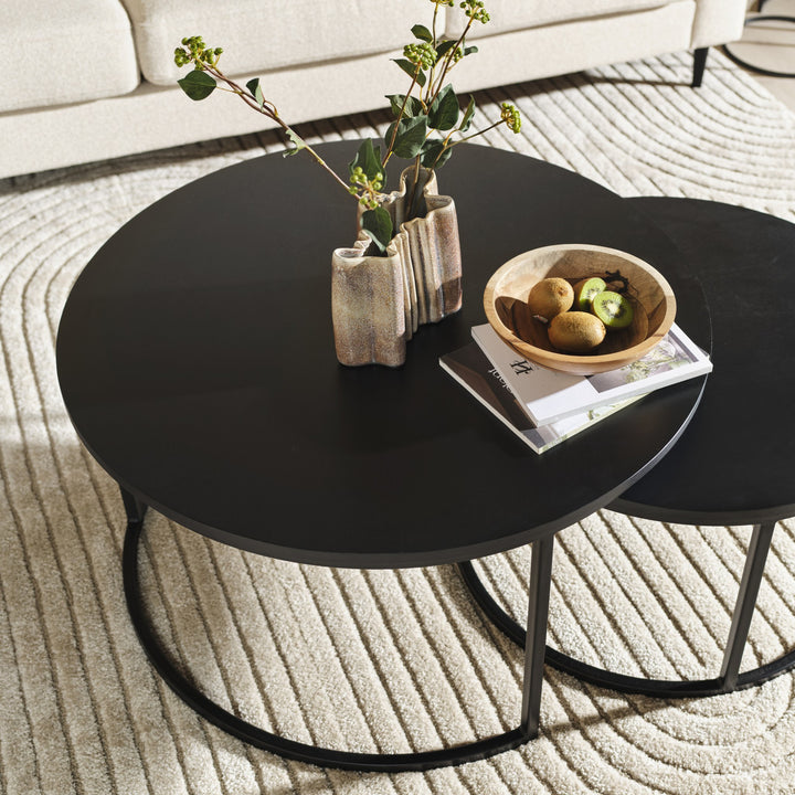 Metro sofabord i sort eikefinér foran lys sofa, dekket med vase, kvister og fruktfat