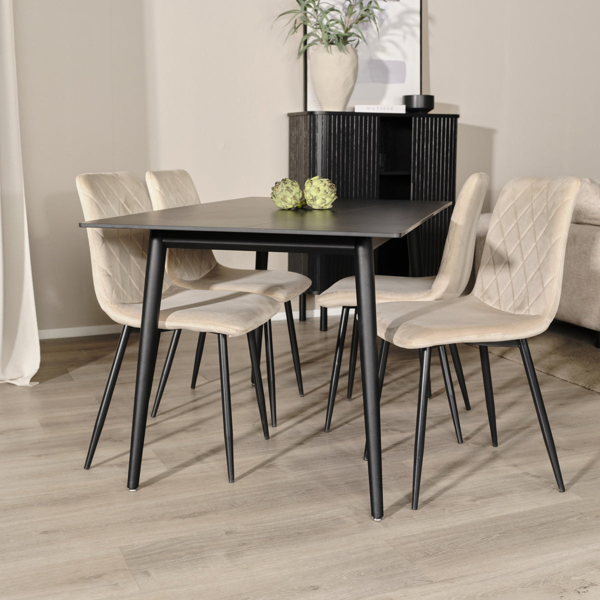 Bari spisestol i beige velur med sorte ben ved sort spisebord i lyst rom