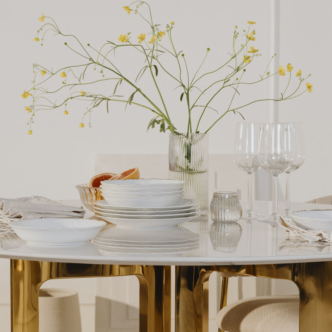 Pisa spisebord med hvit marmorplate og gullbein, dekket med tallerkener og gule blomster