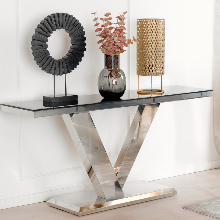 Messina konsollbord med sort glassplate og V-formet krombase, pyntet med vase og lampe