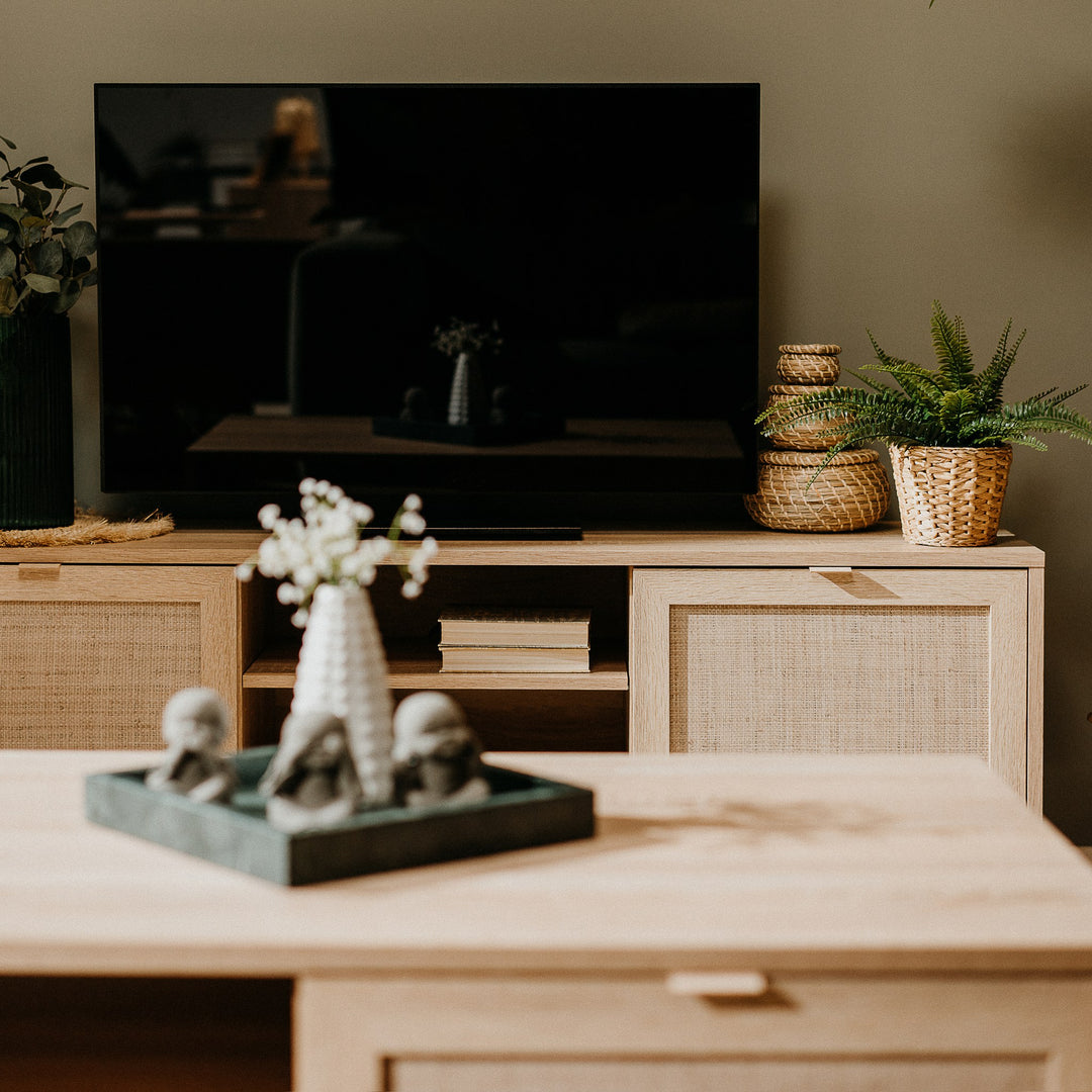 Bali TV-benk i lys eik med rottingdører og TV, i stue med planter og bøker