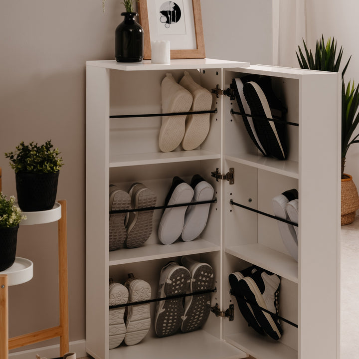 Satos skoskap i hvitt med åpne luker fullt av sko, i lys entré med planter