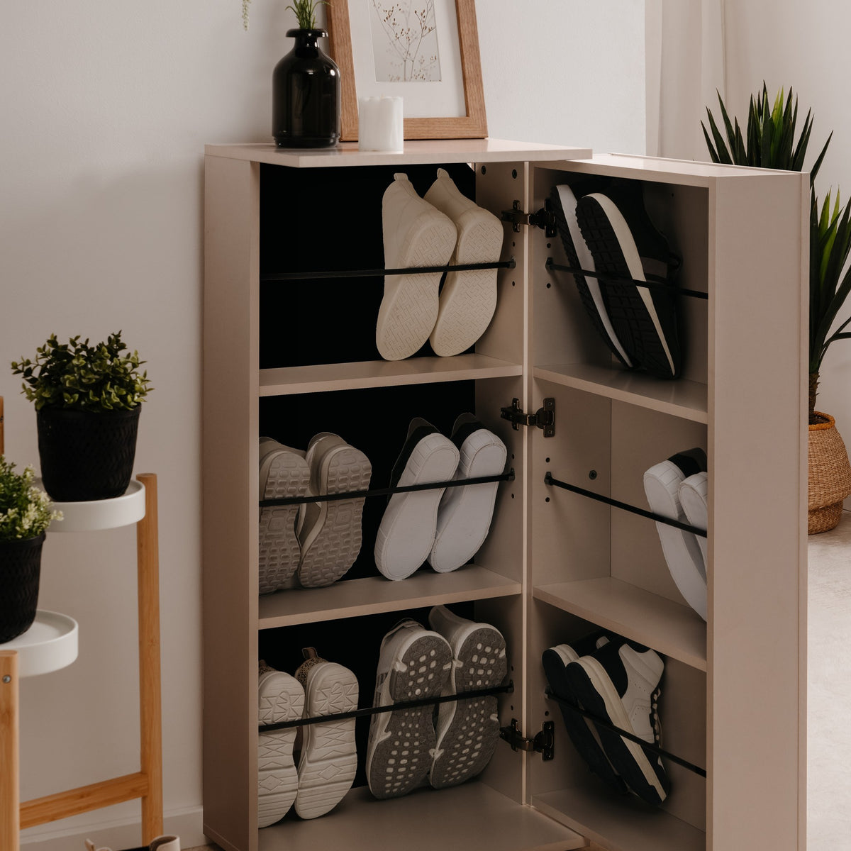 Satos skoskap i beige med åpne dører og skråhyller fulle av sko, i lyst rom med grønne planter