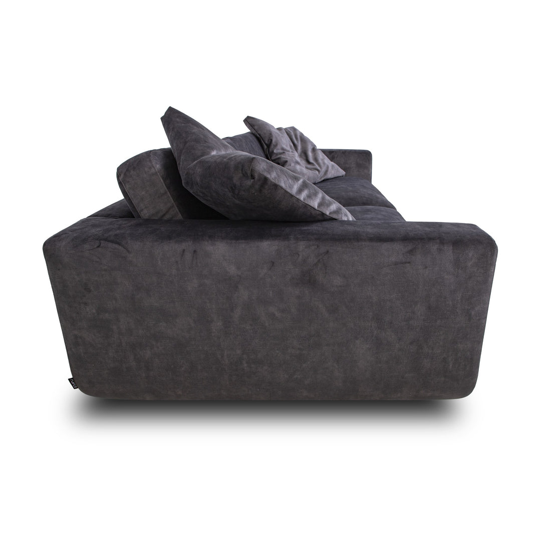 Motive sofa i koksgrå velur, sett fra siden med løse puter
