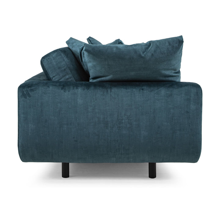 Lazy 3,5-seter sofa i petroleumsblå velur, sett fra siden med løse puter