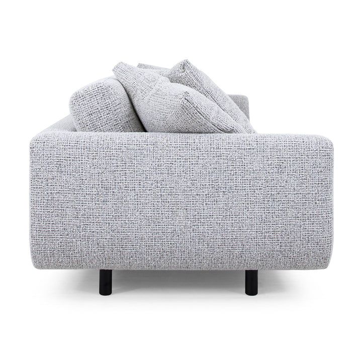 Lazy Sofa i lysegrå melert stoff sett fra siden, med løse puter og svarte ben