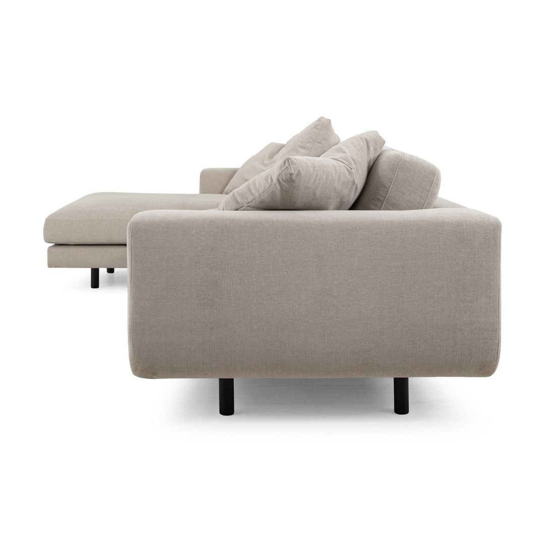 Lazy Sofa i kremhvitt stoff sett fra siden, med sjeselong og svarte ben
