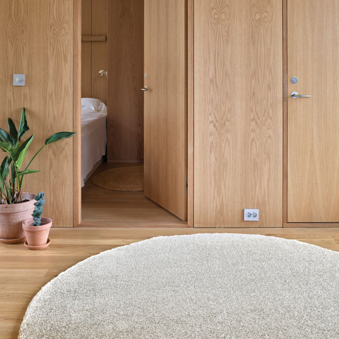 InHouse Spectrum teppe rundt i sand på tregulv i soverom med eikegarderobe og planter
