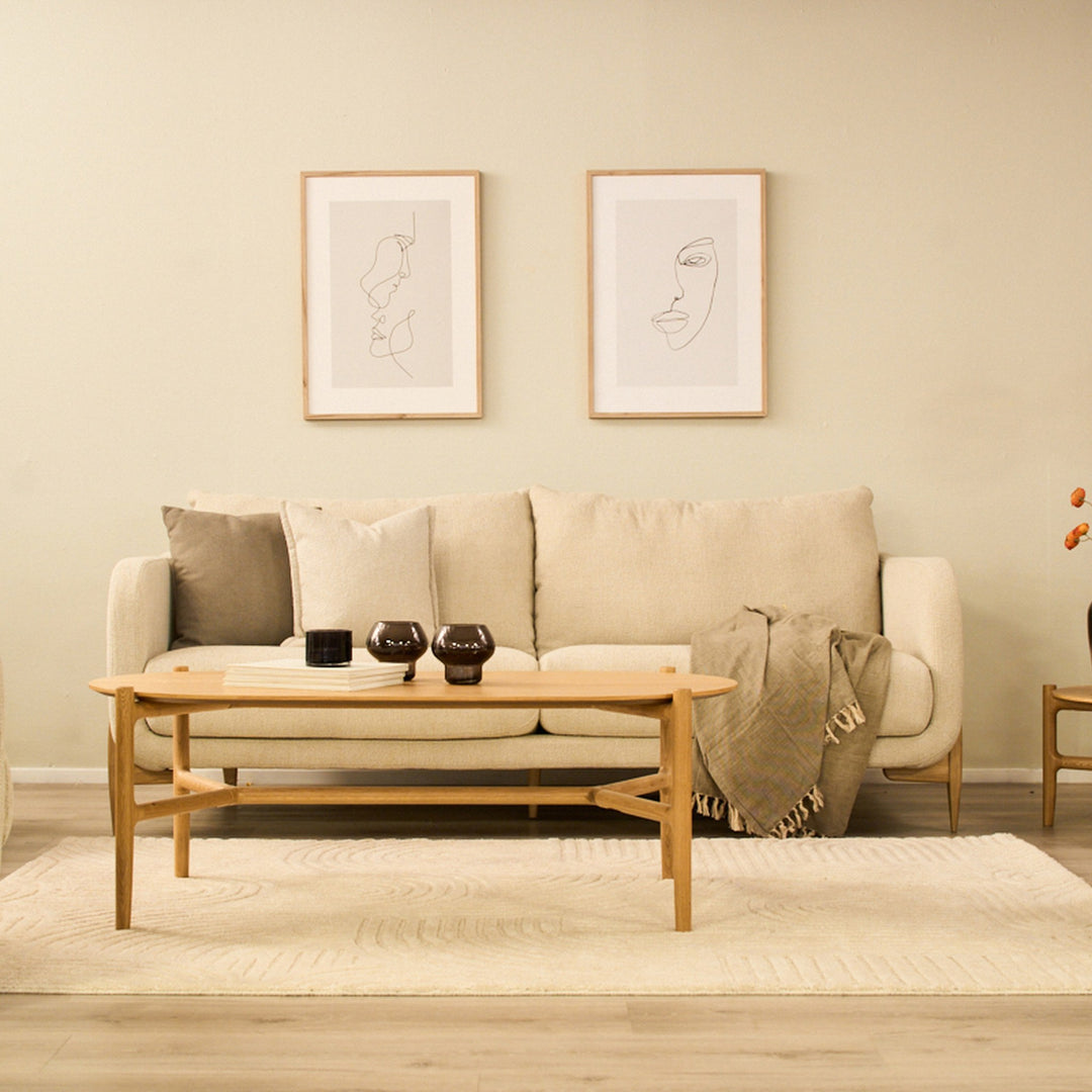 Inhouse Lyngen teppe i kremhvitt under sofabord av eik foran beige sofa i lyst stuemiljø