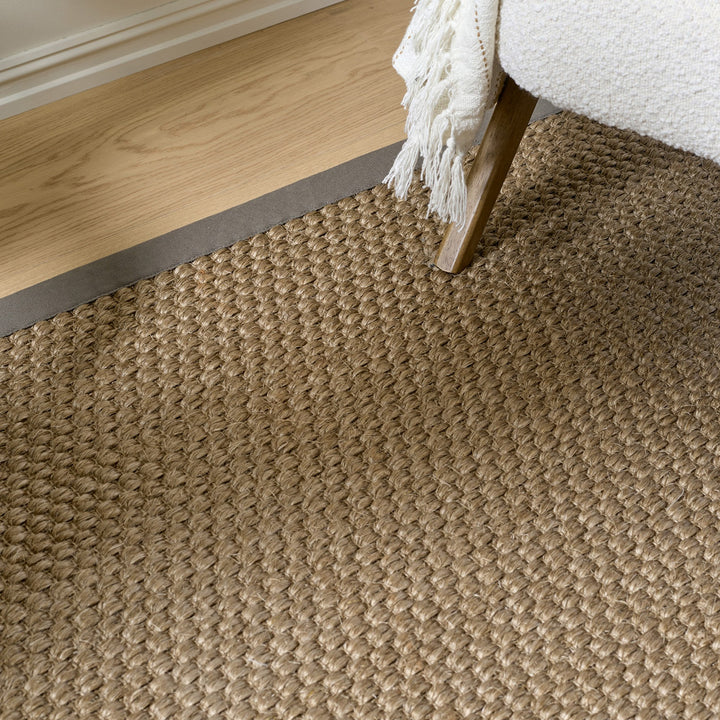 Inhouse Sisal Chunky teppe i taupe, grovflettet sisalteppe på tregulv ved en lys bouclé-møbel