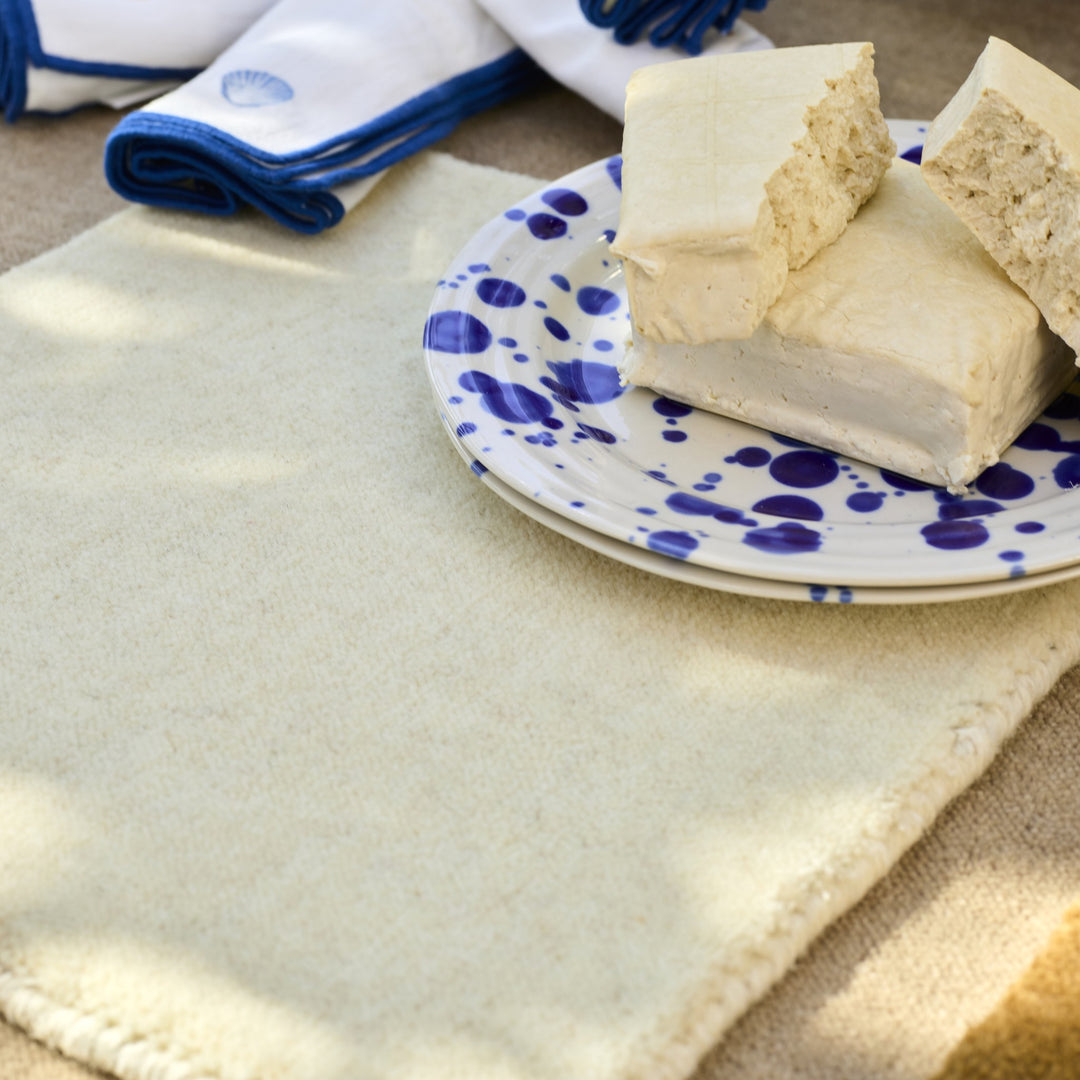 Inhouse Savoy teppe i kremhvit ull med blåprikket tallerken med tofu og blåkantede servietter.