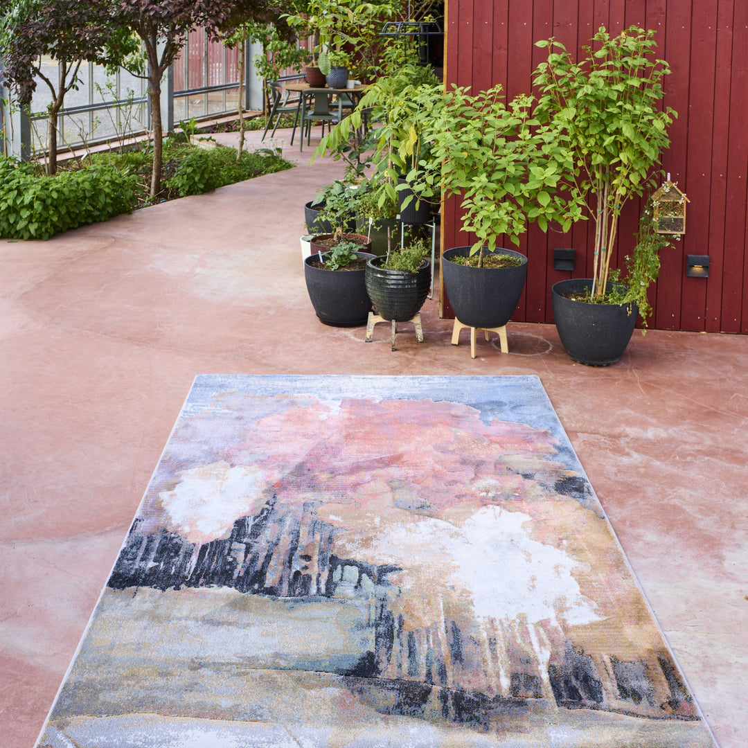 Inhouse Forest teppe i rosa og blått abstrakt mønster på terrakottaterrasse med potteplanter.