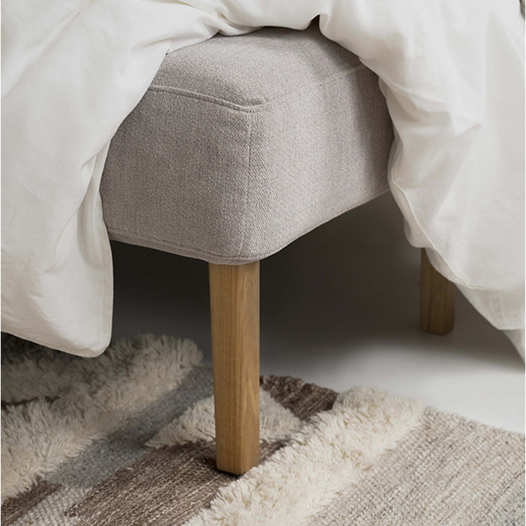 Hovden Sleepy sovesofa i grå, nærbilde av eikeben og hvitt dynetrekk over teppe