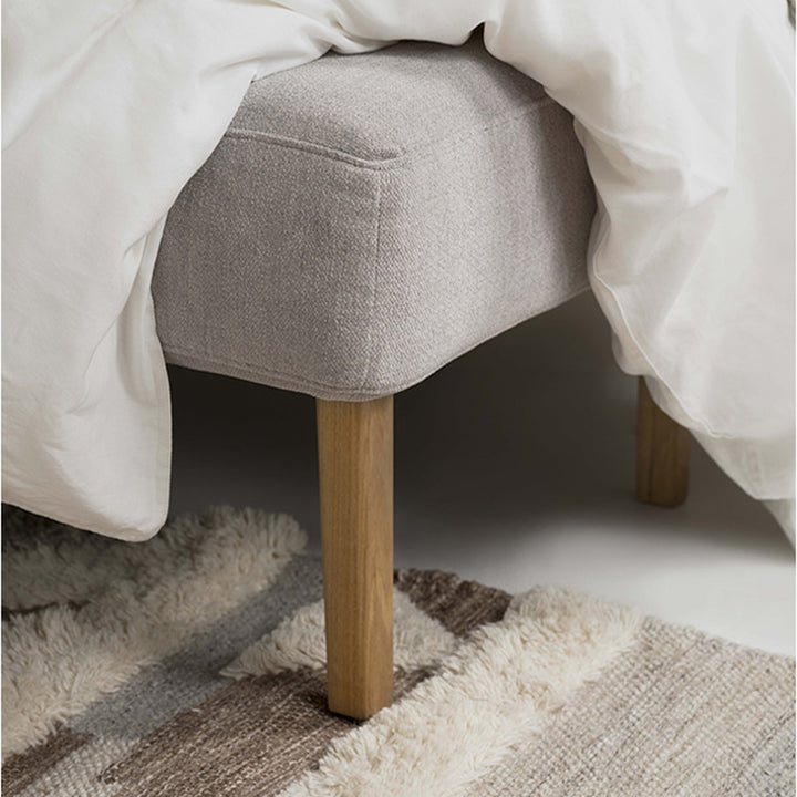 Hovden Sleepy sovesofa i grå, nærbilde av eikeben og hvitt dynetrekk over teppe