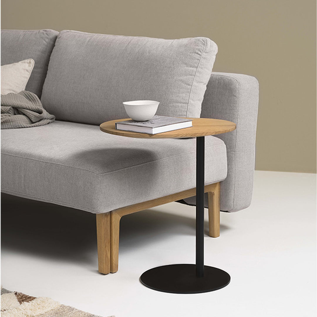 Hovden Sleepy sovesofa i grå, nærbilde med sidebord i eik og svart, bolle og bok
