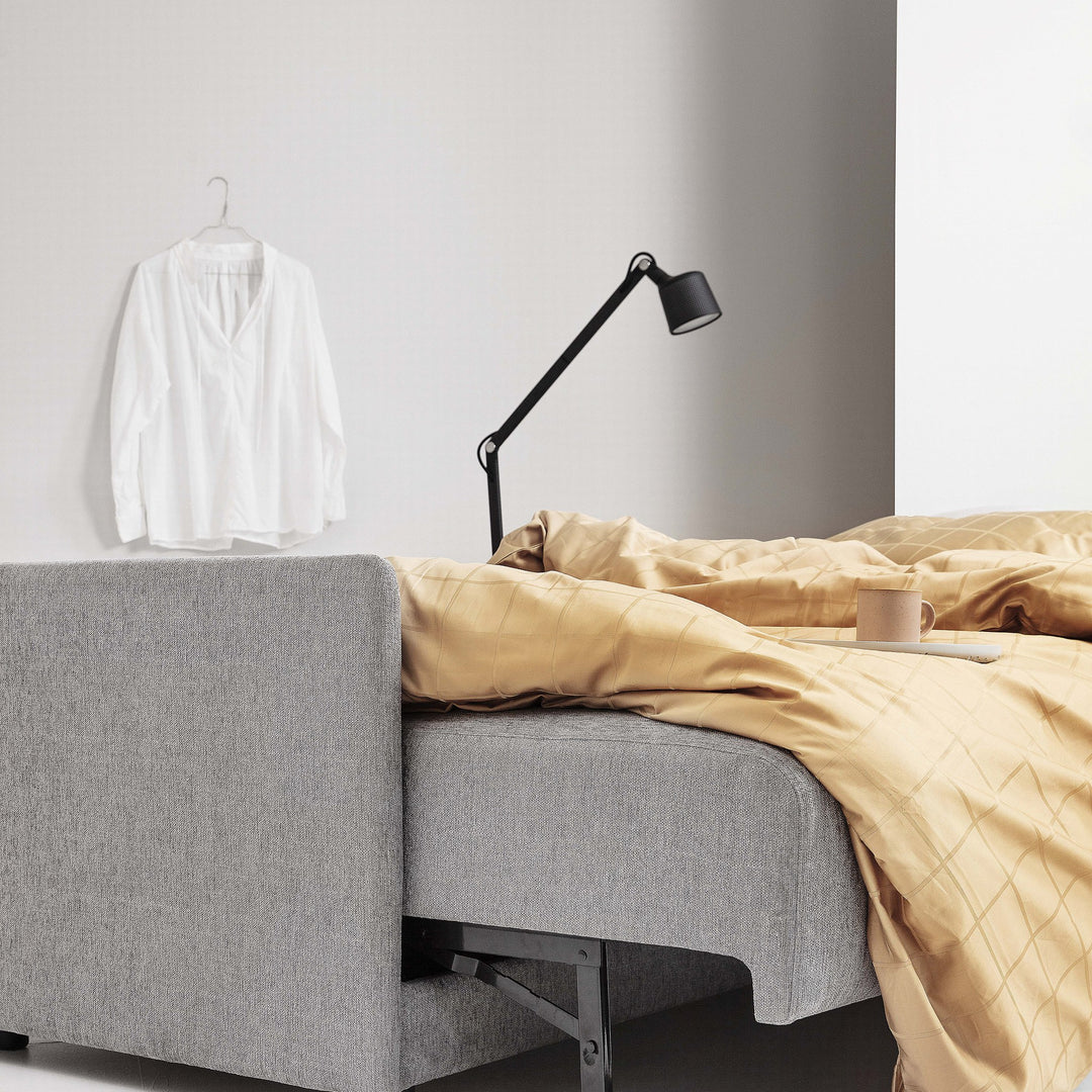 Hovden Flexy sovesofa i grå, nærbilde av armlene med okergult sengetøy