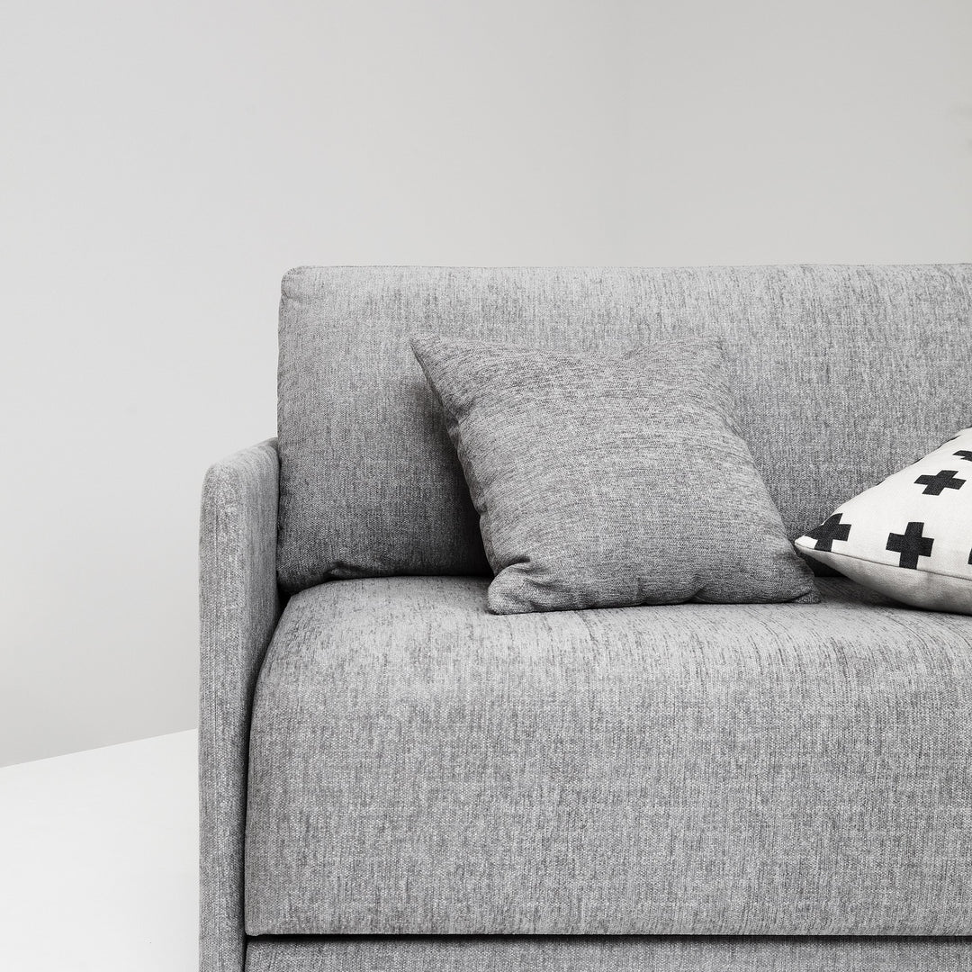 Hovden Flexy sovesofa i grå, nærbilde av sete med grå pute mot lys vegg