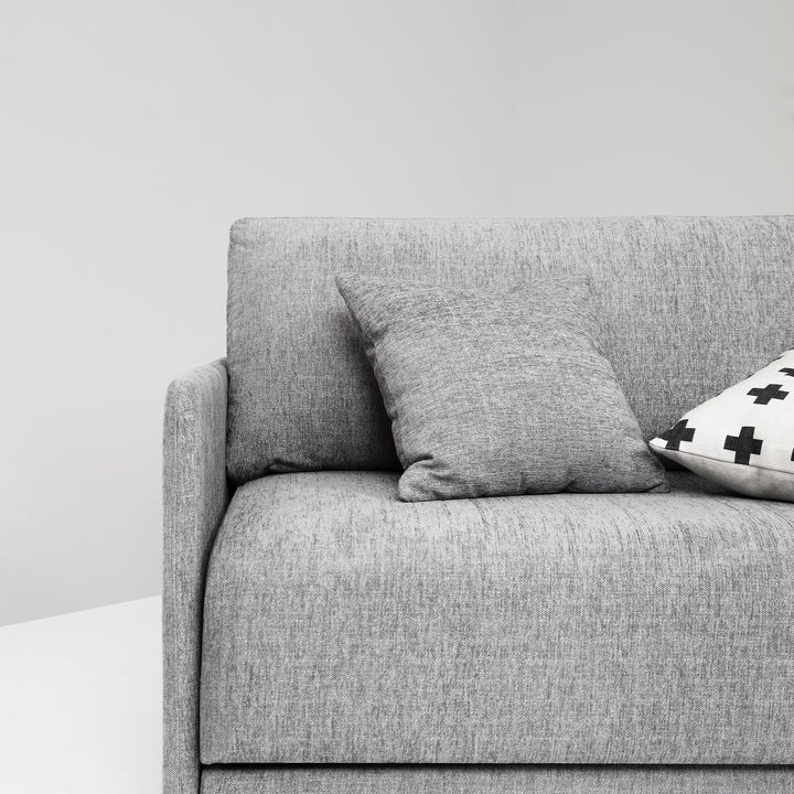 Hovden Flexy sovesofa i grå, nærbilde av sete med grå pute mot lys vegg
