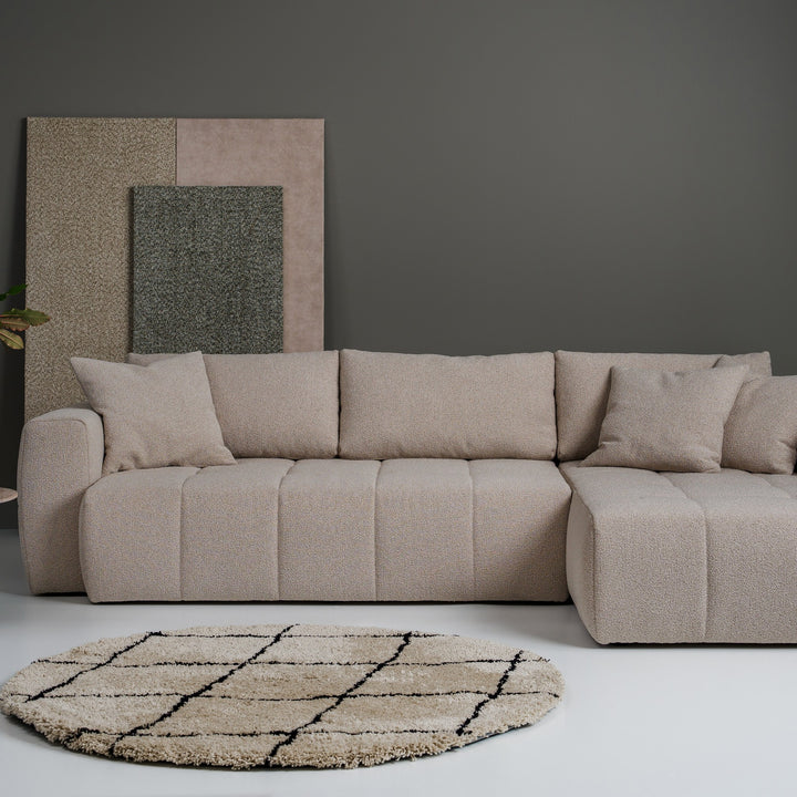 Hovden Fantasy sovesofa i beige bouclé som hjørnesofa i stue med lerret på vegg og rundt teppe.